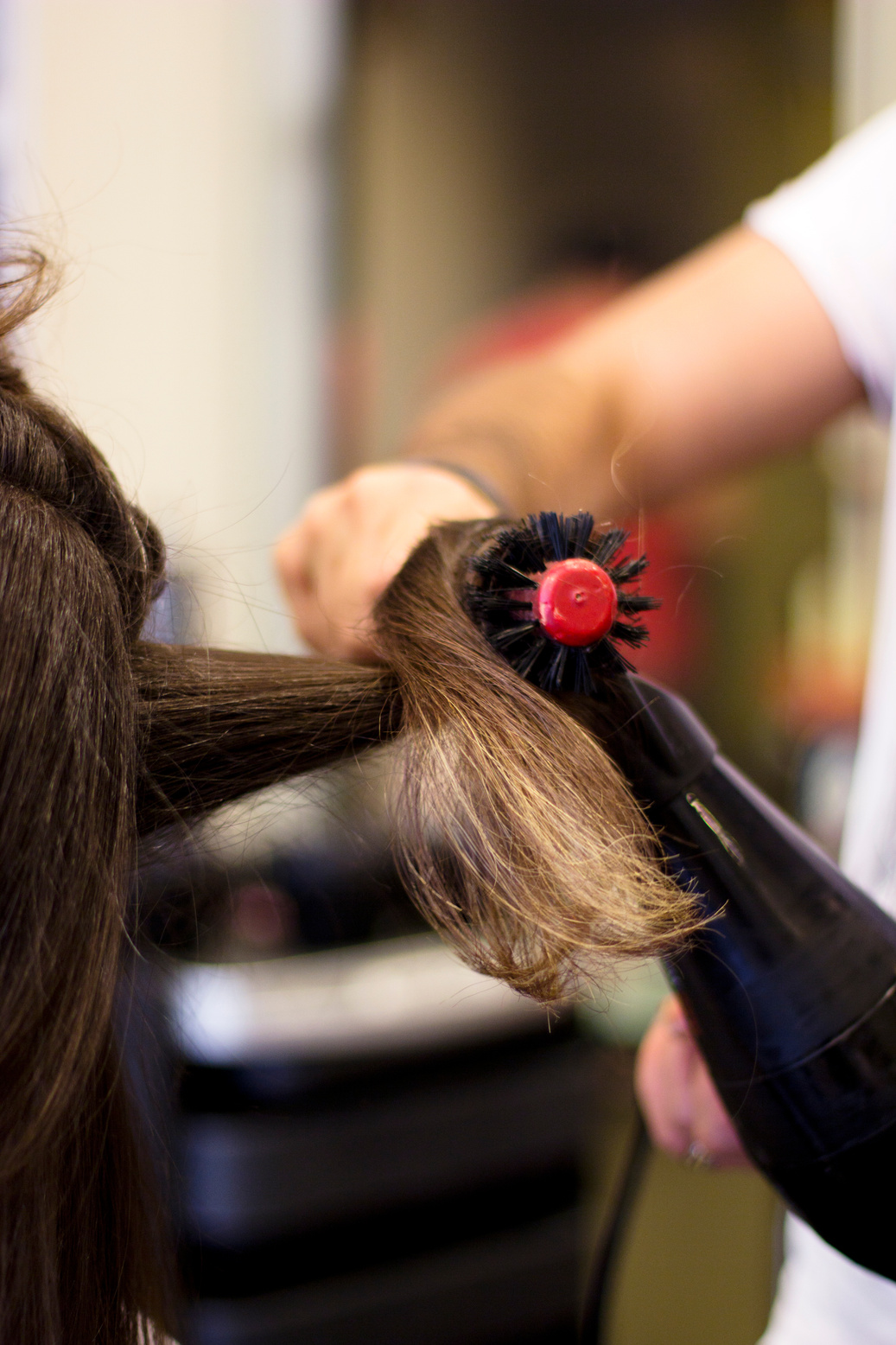 Hairdresser using hair dryer and round brush
